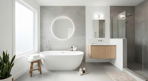 An elegant bathroom with large format grey stone tiles and a freestanding modern bathtub. High-key lighting creates a bright and airy atmosphere, emphasizing the clean lines and premium materials used in the interior design.
