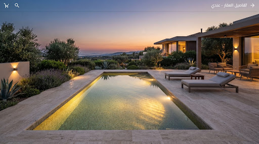 A view of a modern private swimming pool at sunset, illuminated by warm underwater lights. The surrounding terrace is paved with light-colored stone and features minimal outdoor furniture. The mood is calm and exclusive.